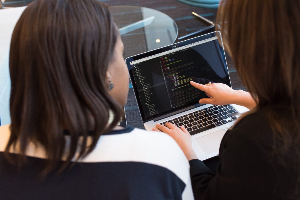 two women coding on a laptop